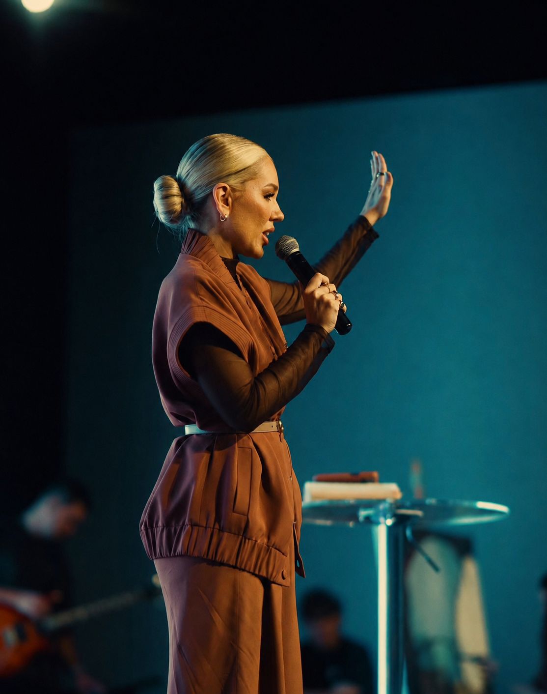 Pastora Natasha Serigatto ministrando, com o microfone na mão e o braço erguido.
